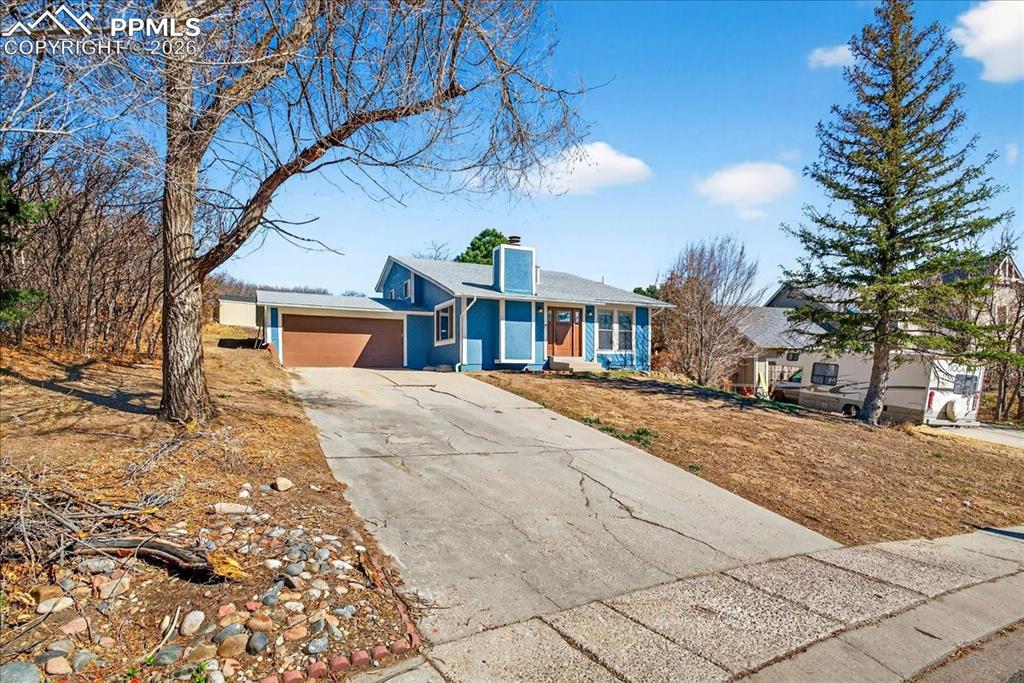 Image 2 of 49: View of front of property featuring a chimney, driveway, and an attached ga