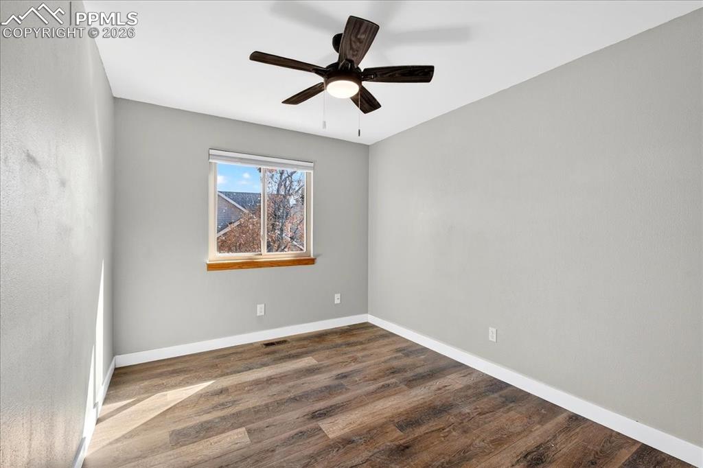 Image 29 of 49: Empty room with dark wood-style floors and a ceiling fan
