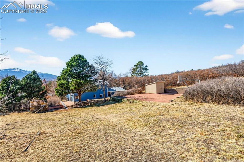 Image 37 of 49: View of grassy yard with a patio, a storage shed, and a mountain view