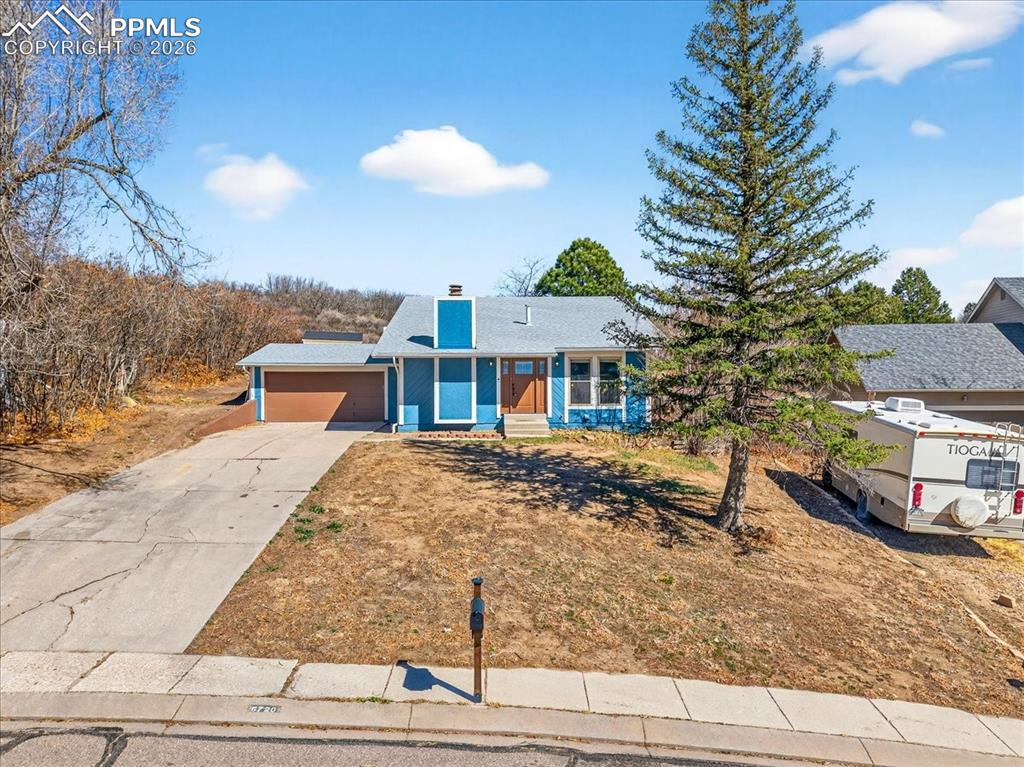 Image 39 of 49: View of front facade featuring a chimney, driveway, and a garage