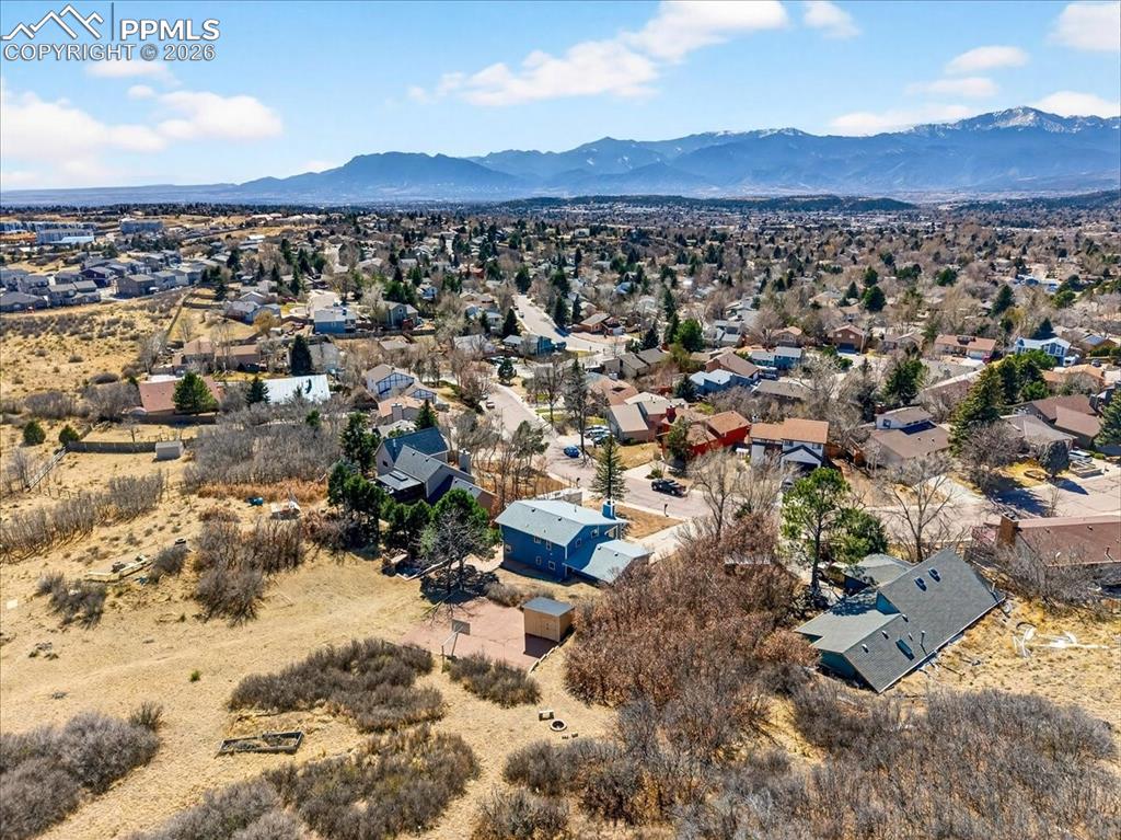 Image 44 of 49: Aerial view of residential area featuring a mountainous background