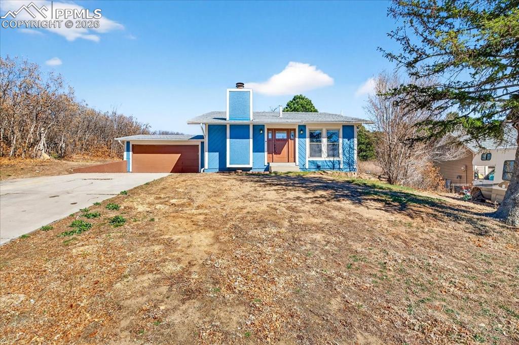 Image 45 of 49: View of front facade featuring a chimney and concrete driveway