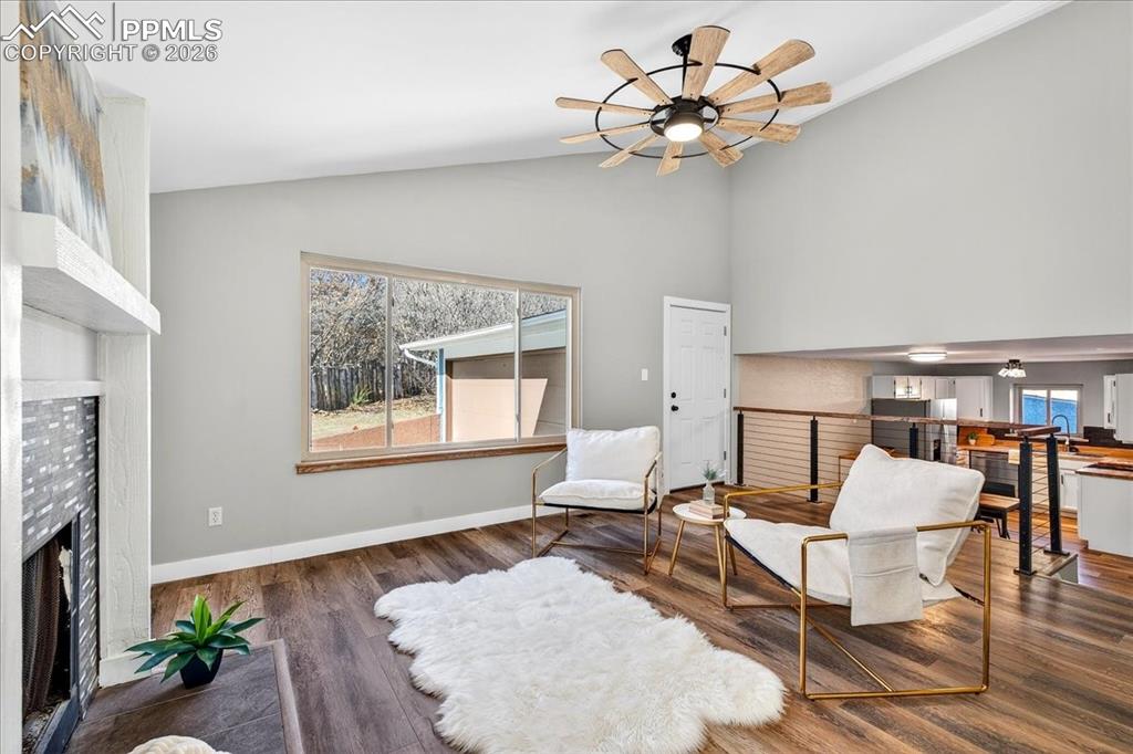 Image 9 of 49: Sitting room with a fireplace, ceiling fan, wood finished floors, and vault