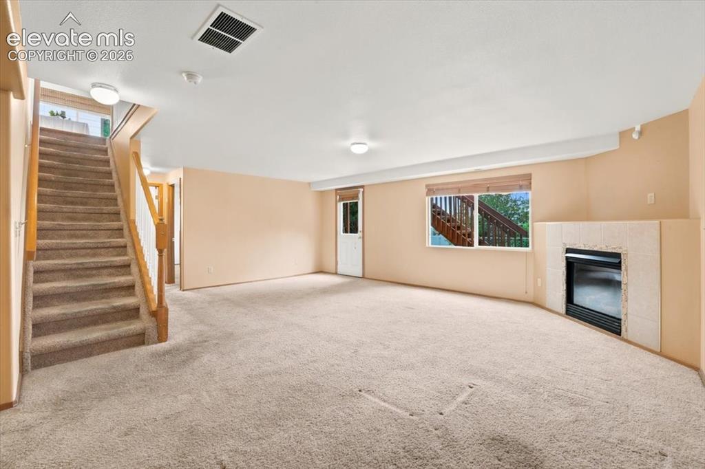Image 46 of 50: Stairs to the basement, the walkout door, Large window, and fireplace