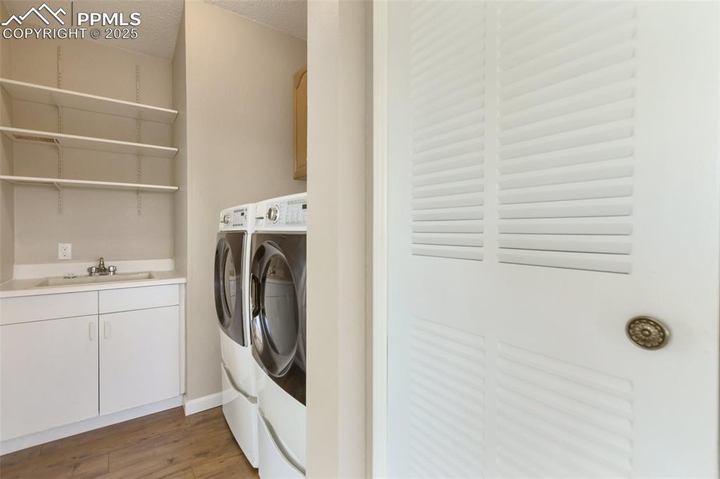 Image 14 of 38: Laundry room with front loading Kenmore washer dryer set. Utility sink and