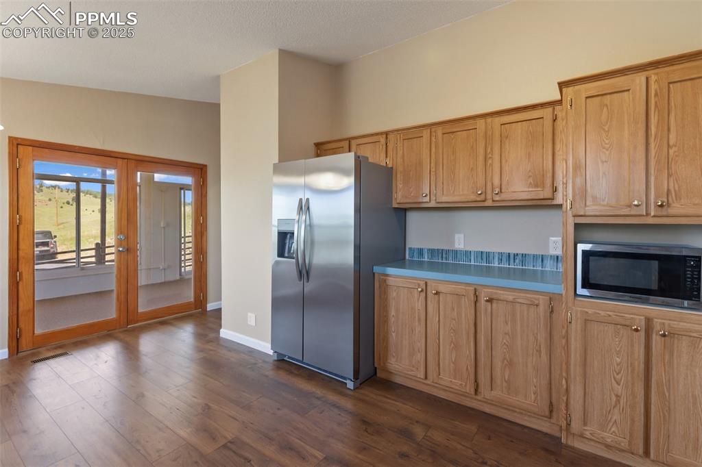 Image 18 of 38: French door access from the kitchen to the sunroom. Plenty of cabinet space