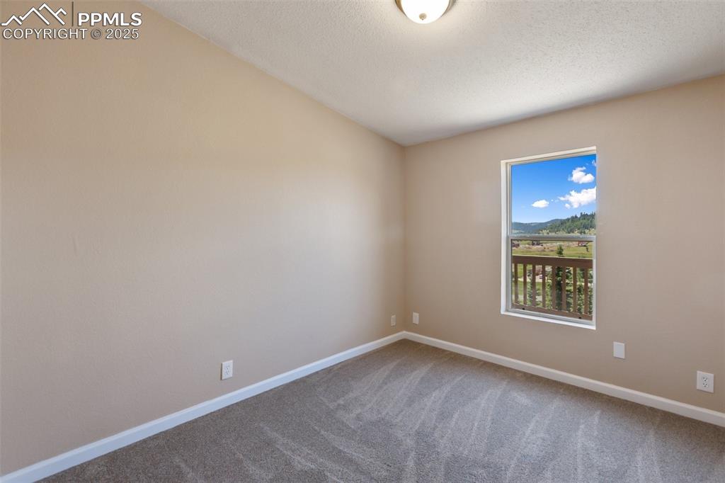 Image 34 of 38: Third bedroom with southern views off the deck side. New paint and carpet.