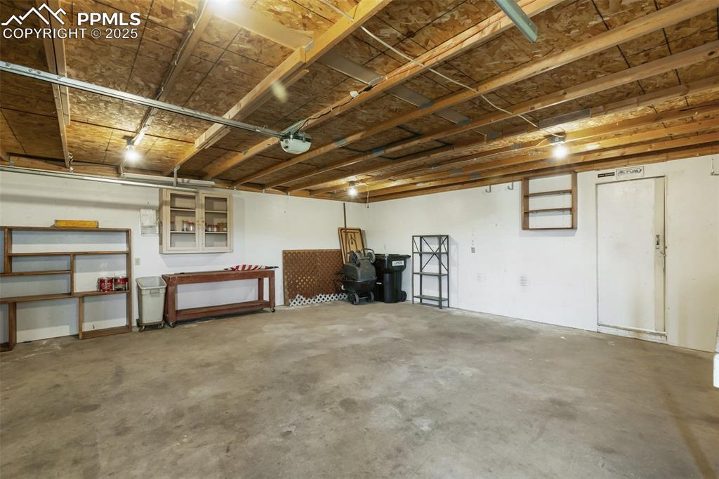 Image 36 of 38: Full oversized garage with workbenches, cabinet spaces, loft storage, and t