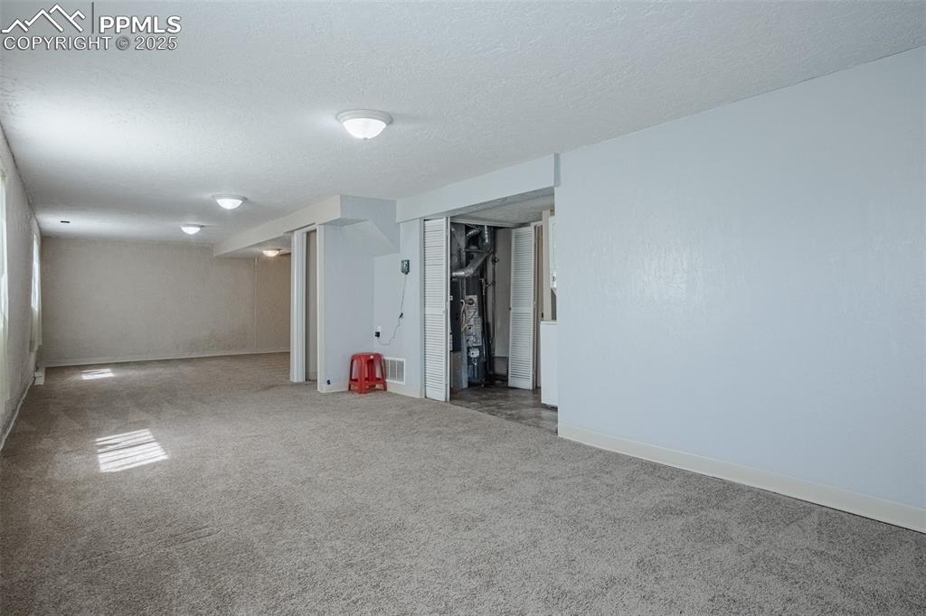 Image 36 of 44: Finished below grade area with a textured ceiling, carpet flooring, baseboa