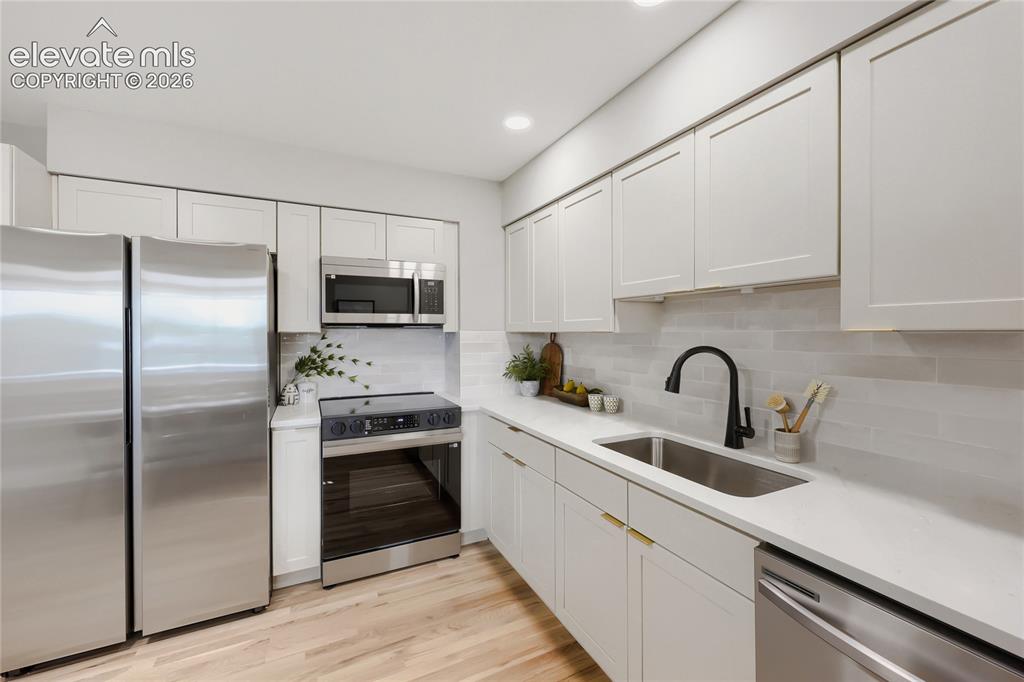 Image 14 of 42: Modern kitchen featuring light wood-finish flooring, white shaker cabinetry