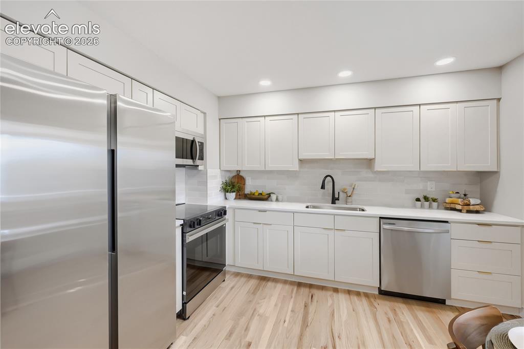 Image 15 of 42: Modern kitchen featuring light wood-finish flooring, white cabinetry, integ