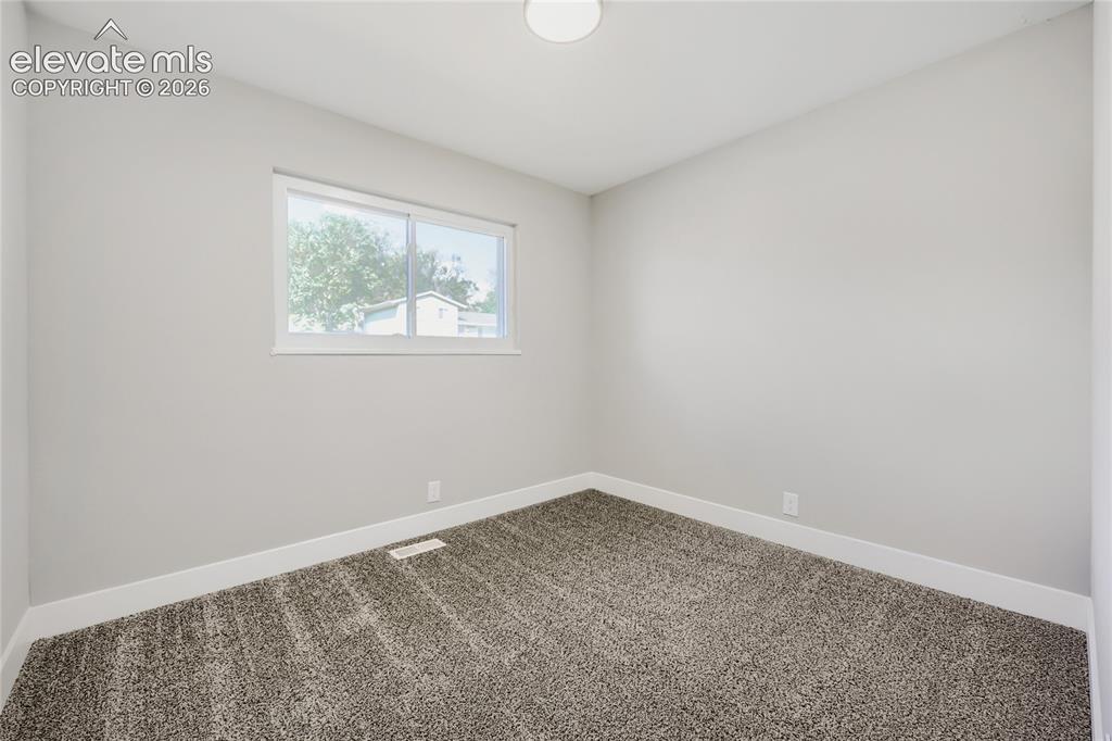 Image 19 of 42: Neutral wall paint, carpet flooring, window with white trim, and a flush mo