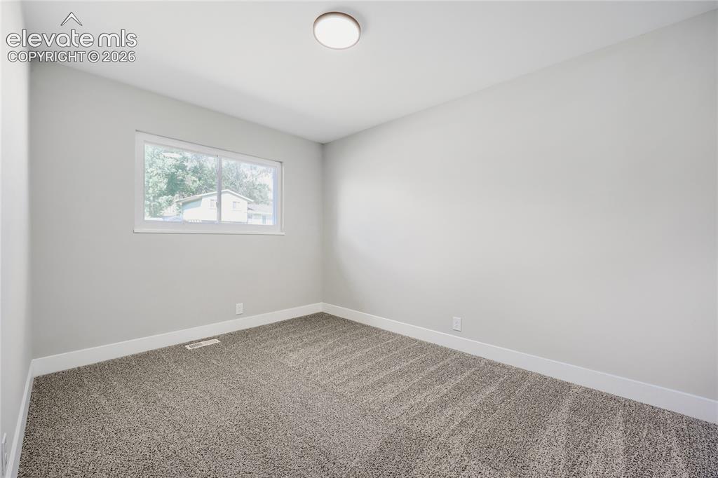Image 21 of 42: Neutral tone walls with white trim, gray carpet flooring, and a single wind