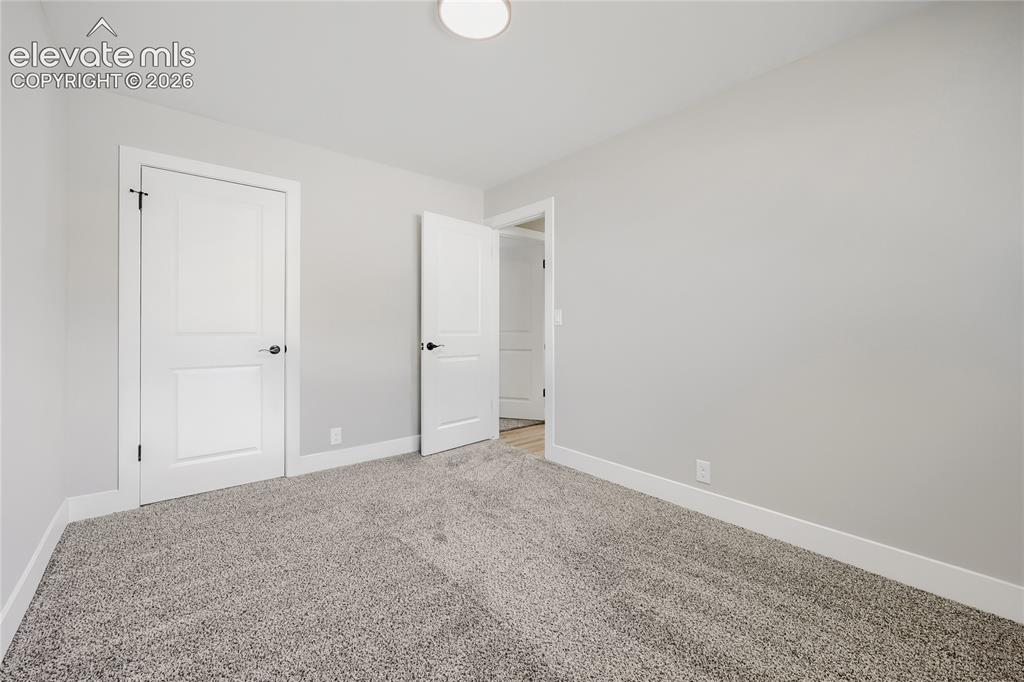 Image 22 of 42: Light gray wall paint, two paneled doors with black hardware, white trim, a