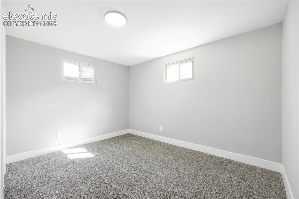 Image 23 of 42: Recessed lighting, light gray wall finish, two small windows, gray carpet f