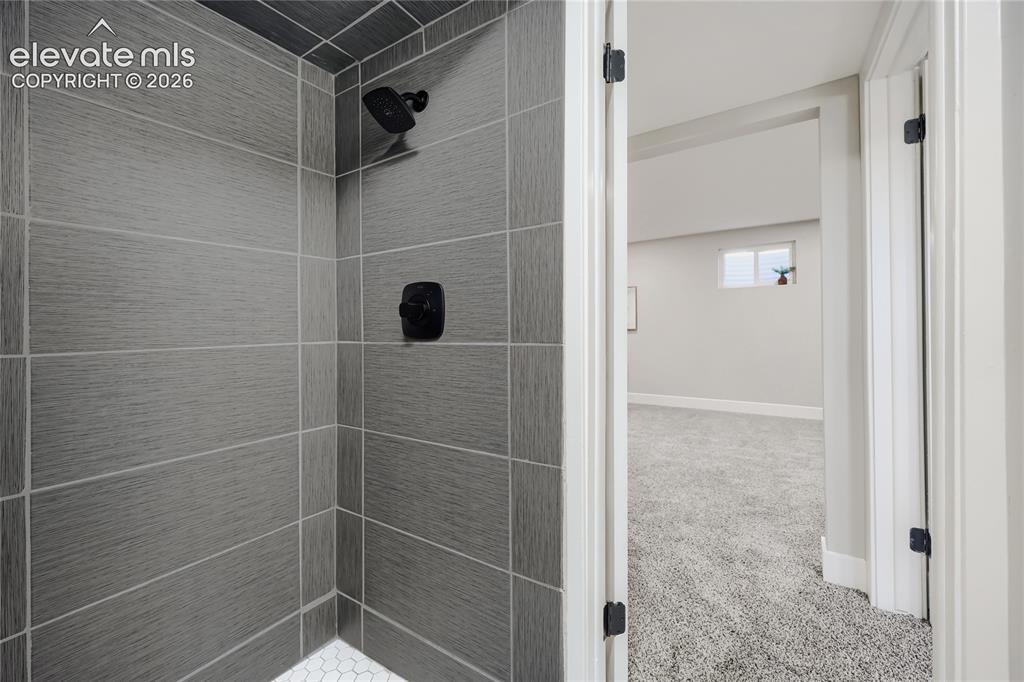 Image 29 of 42: Shower stall with gray horizontal tile, a black showerhead, and a black fau
