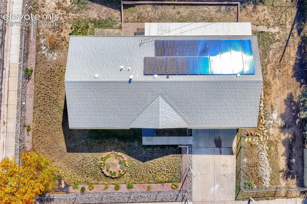 Image 39 of 42: Gable roof with asphalt shingles, solar panel array, concrete driveway, and