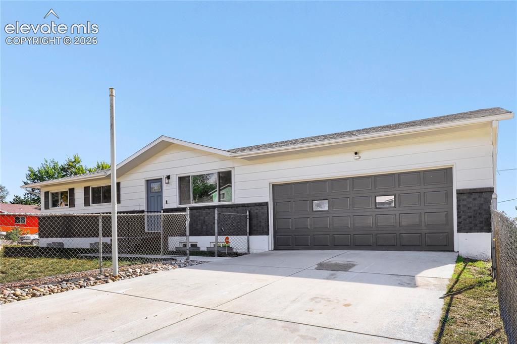Image 5 of 42: Concrete driveway, attached garage with panel door, white exterior siding, 