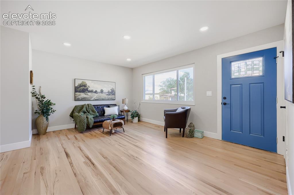 Image 8 of 42: Light wood-finish flooring, recessed lighting, and a blue paneled entry doo