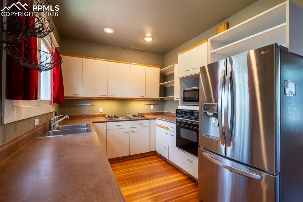 Image 10 of 24: Kitchen featuring open shelves, stainless steel appliances, white cabinets,