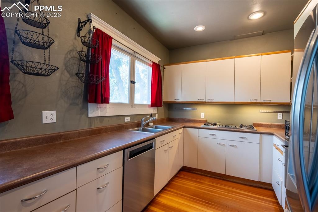 Image 11 of 24: Kitchen with stainless steel appliances, white cabinetry, light wood-type f