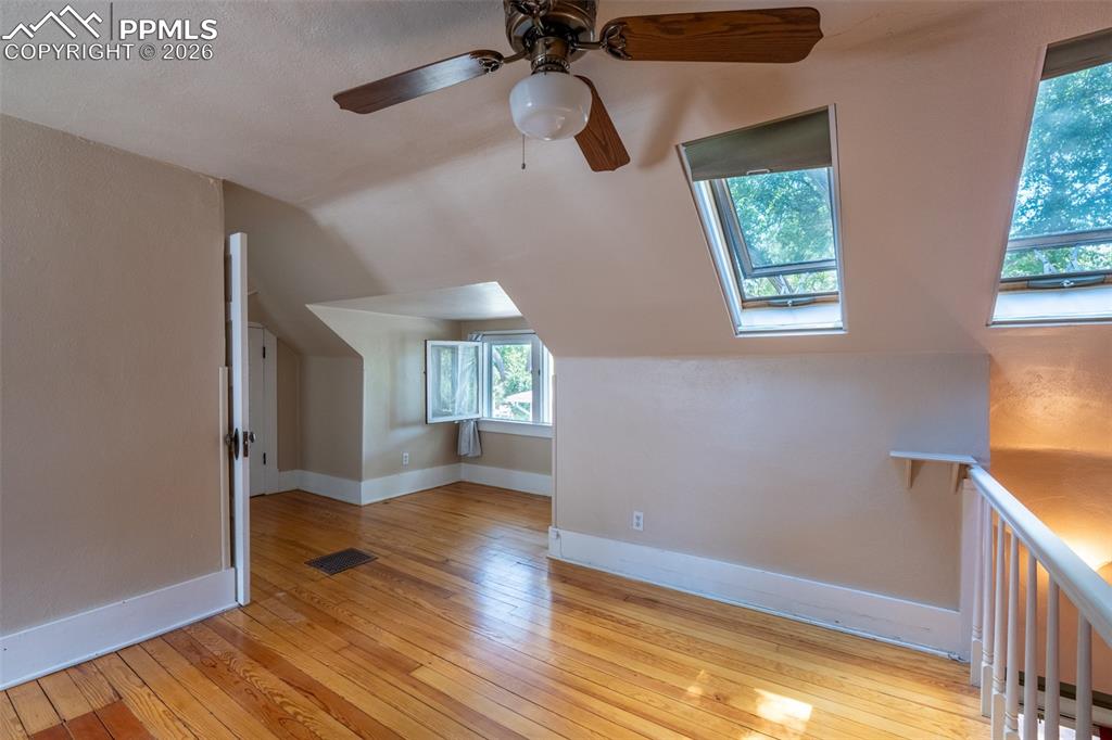 Image 17 of 24: Primary bedroom with light wood finished floors, a skylight, lofted ceiling
