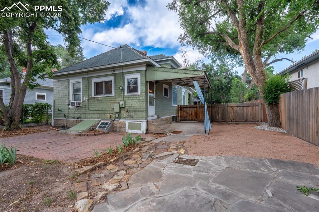 Image 19 of 24: Rear view of house with a patio, a fenced backyard, and a shingled roof