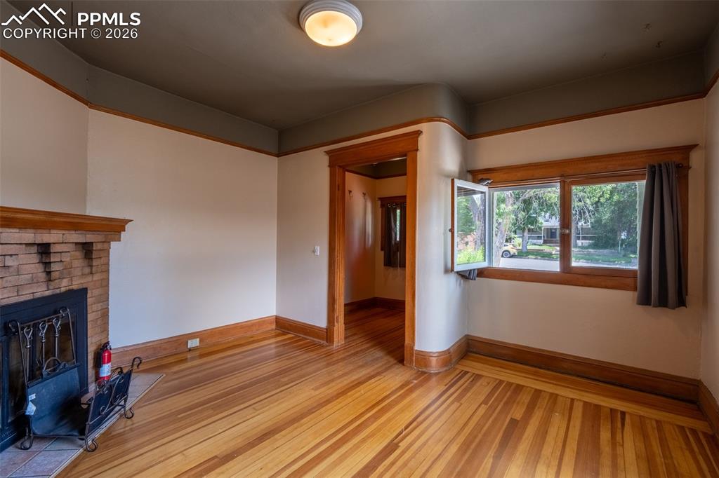 Image 6 of 24: Living room with light wood-style flooring and a brick fireplace