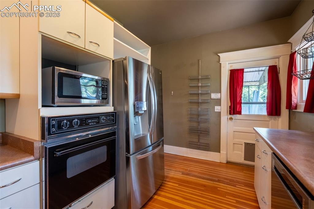 Image 9 of 24: Kitchen featuring stainless steel appliances, white cabinets, light wood-ty