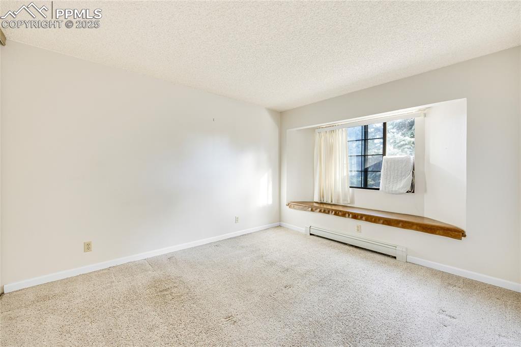 Image 10 of 17: Carpeted spare room with a textured ceiling and baseboard heating