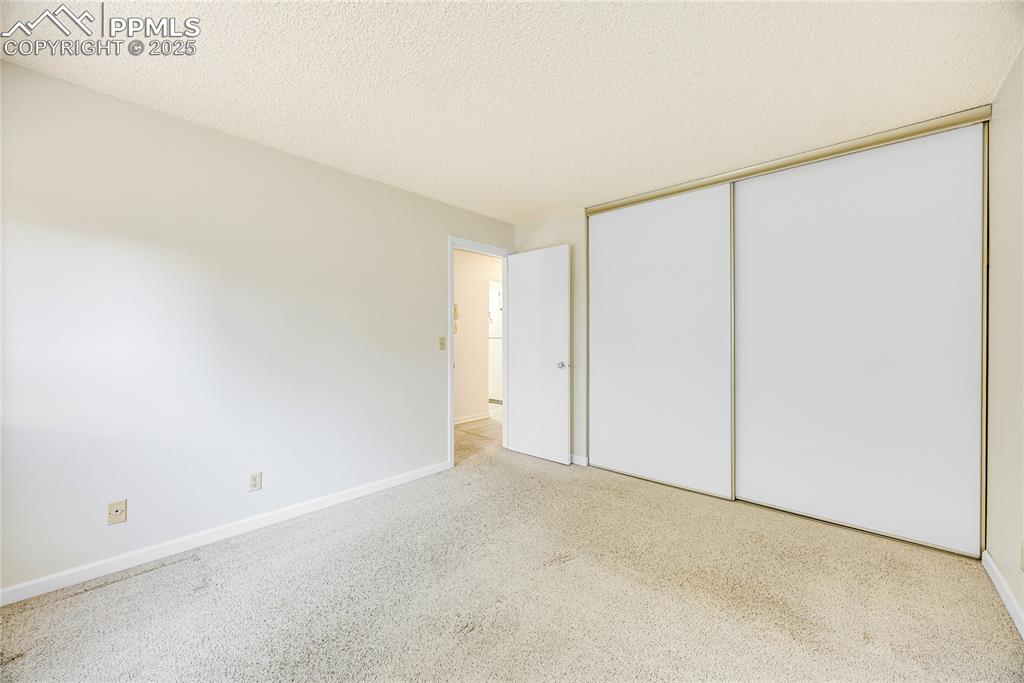 Image 12 of 17: Unfurnished bedroom featuring a textured ceiling, carpet, and a closet