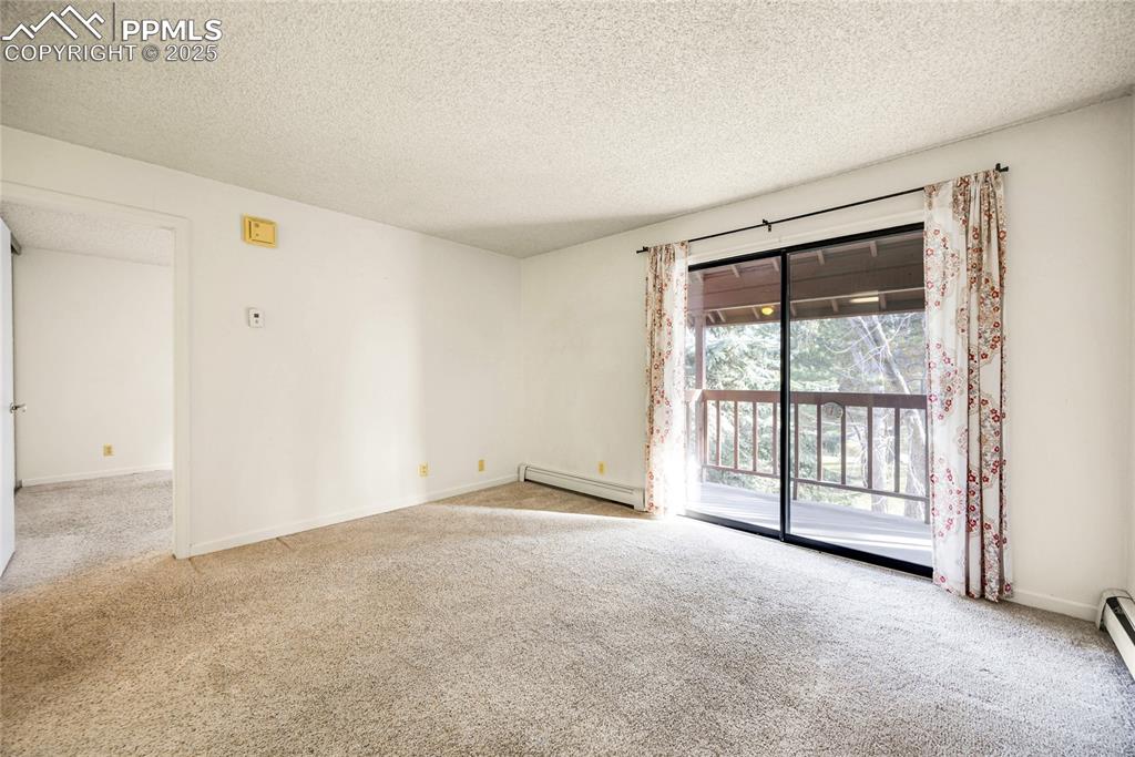 Image 8 of 17: Spare room with carpet, a textured ceiling, and a baseboard radiator