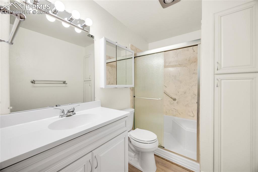Image 9 of 17: Full bath featuring vanity, a shower stall, and light wood-type flooring