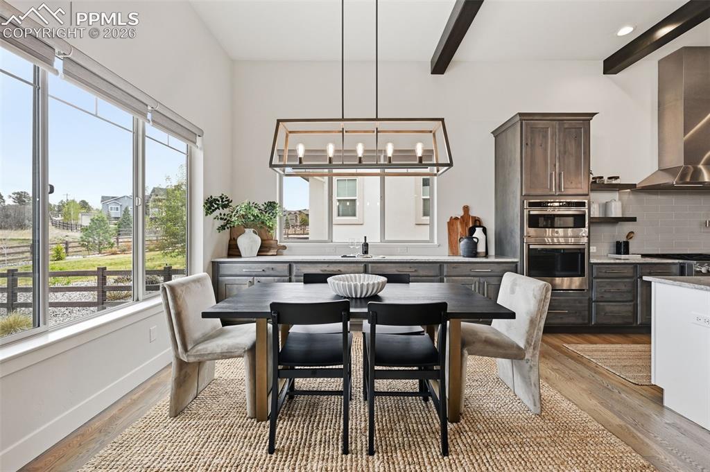 Image 11 of 39: Dining area with vaulted ceilings featuring exposed beams and a linear chan