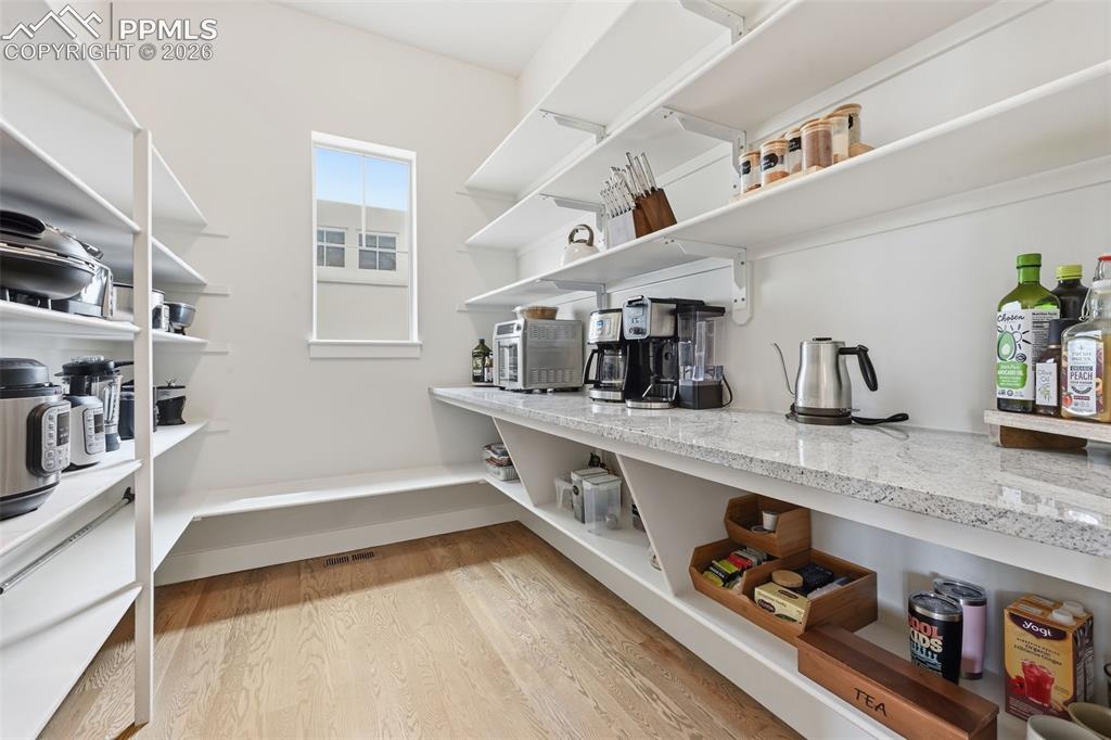 Image 12 of 39: Walk-in pantry #1 featuring extensive white shelving, a granite-finish coun
