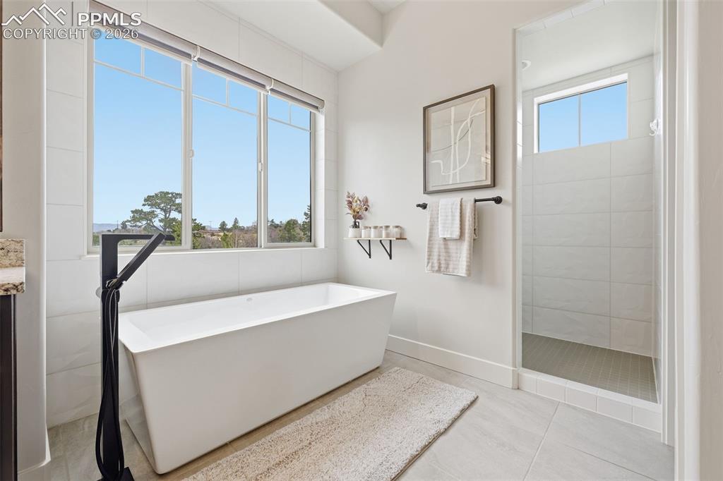 Image 18 of 39: Freestanding soaking tub with a matte black floor-mounted faucet, expansive