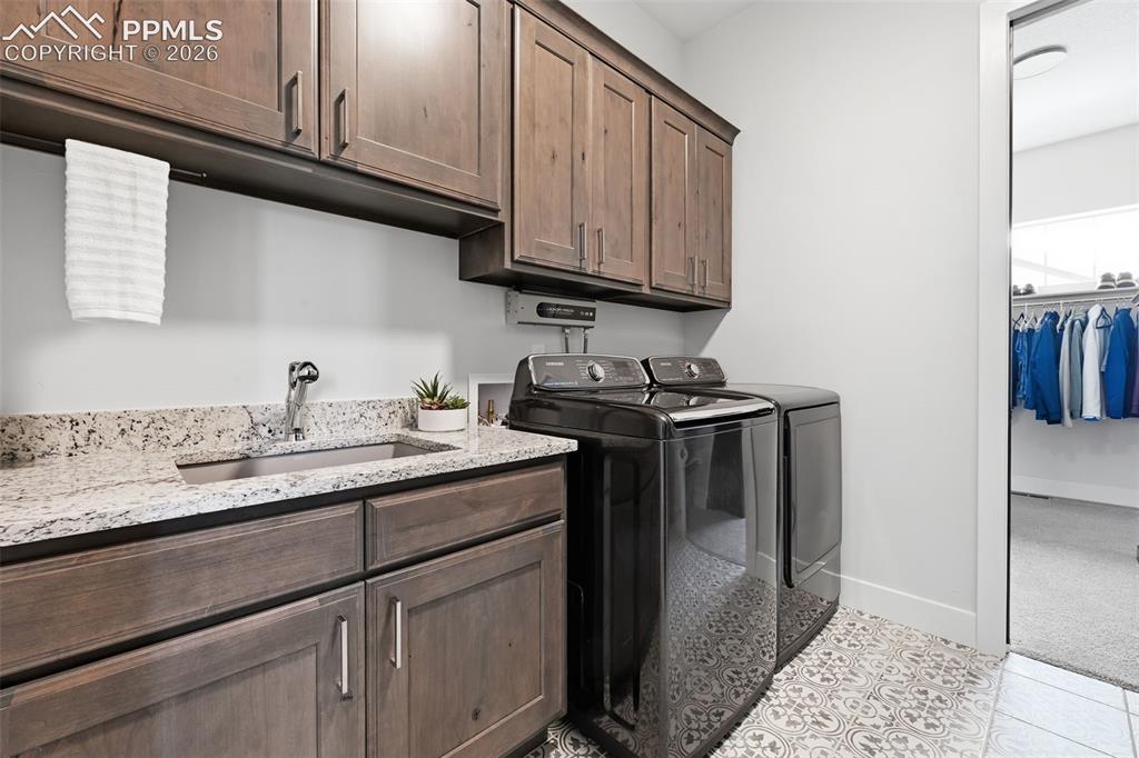 Image 21 of 39: Main level laundry room featuring patterned tile flooring, built-in cabinet