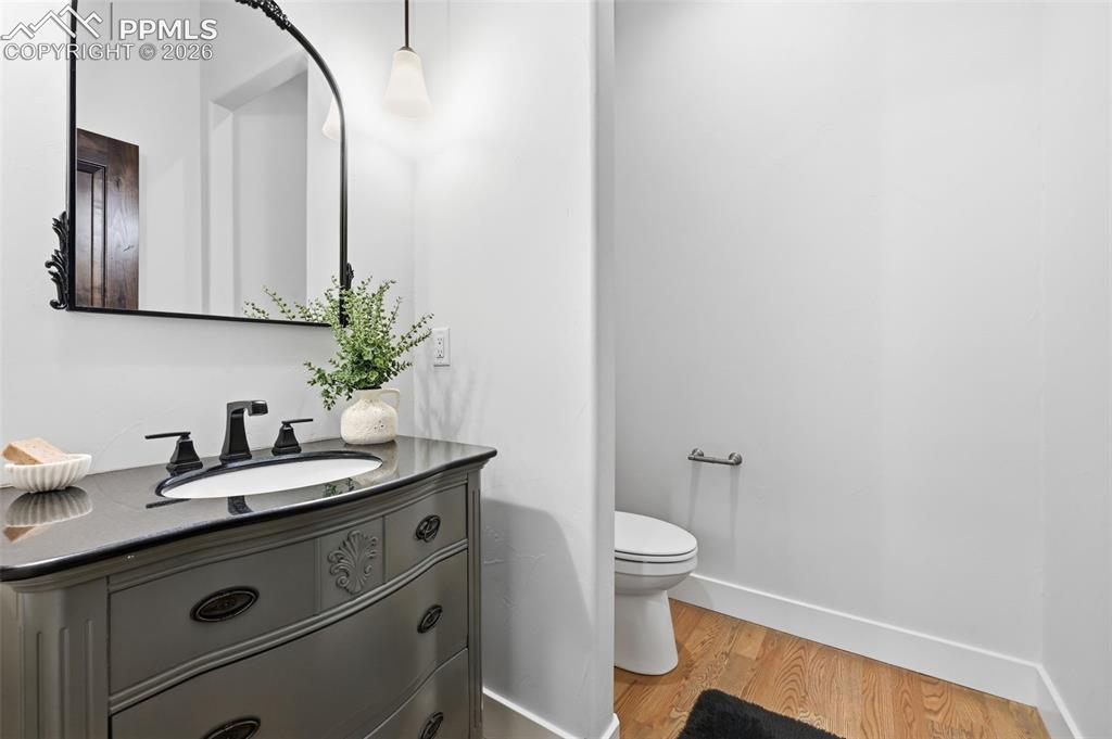 Image 22 of 39: Main level powder room with a decorative vanity, dark countertop, and under