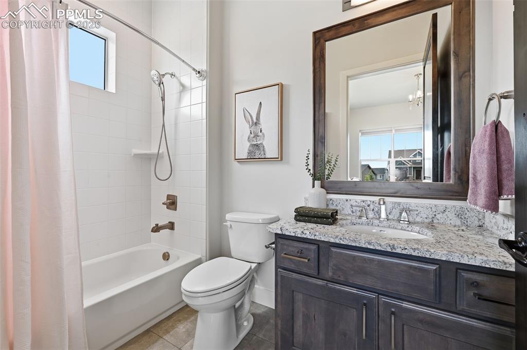 Image 25 of 39: En suite secondary bathroom featuring a dark wood-finish vanity with a gran