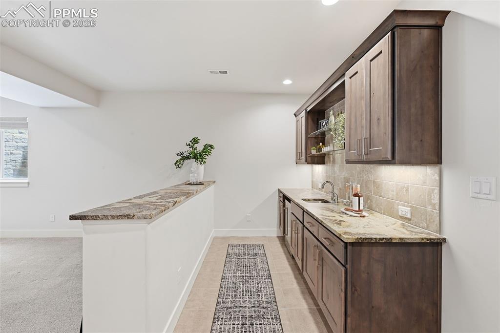 Image 27 of 39: Kitchenette featuring light-toned countertops, wood-finish cabinetry, stain