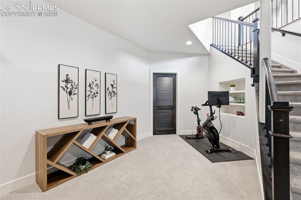 Image 28 of 39: Carpeted staircase with dark wood newel posts and metal balusters