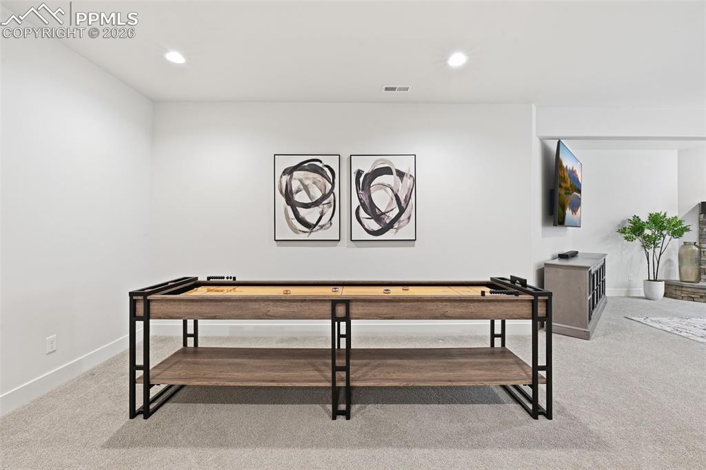 Image 29 of 39: Open-concept recreation area featuring light-toned carpeting, recessed ligh