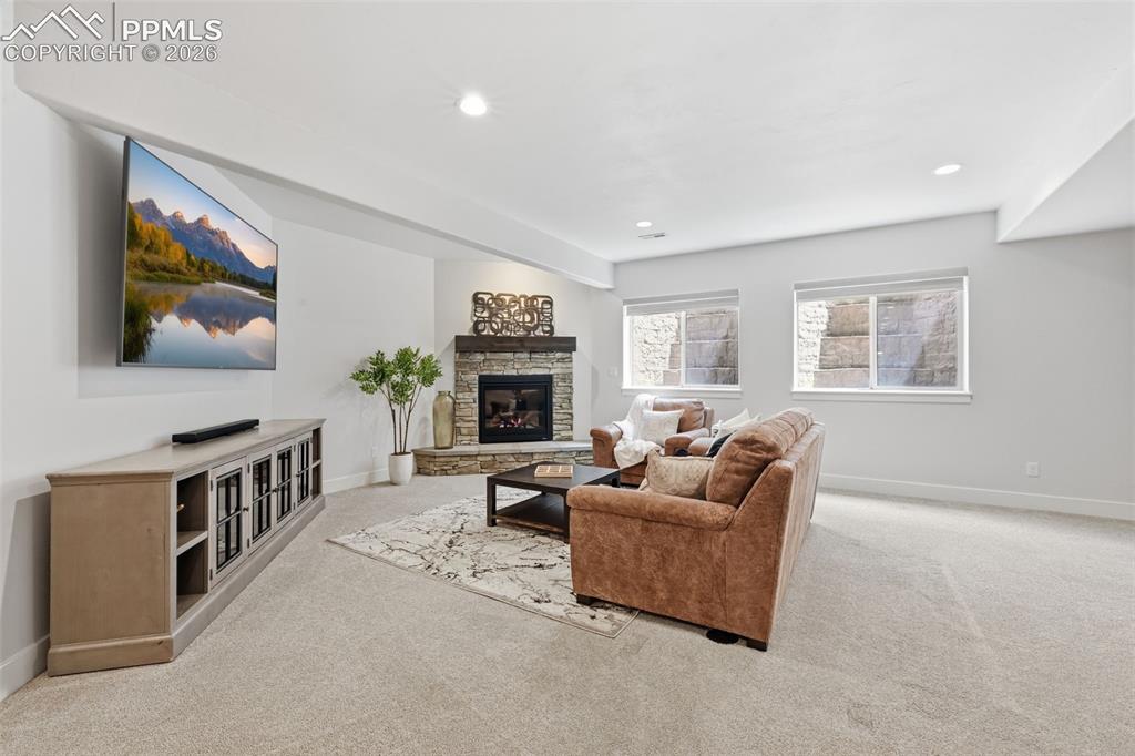 Image 30 of 39: Spacious living area featuring a stone-clad fireplace with a hearth, recess