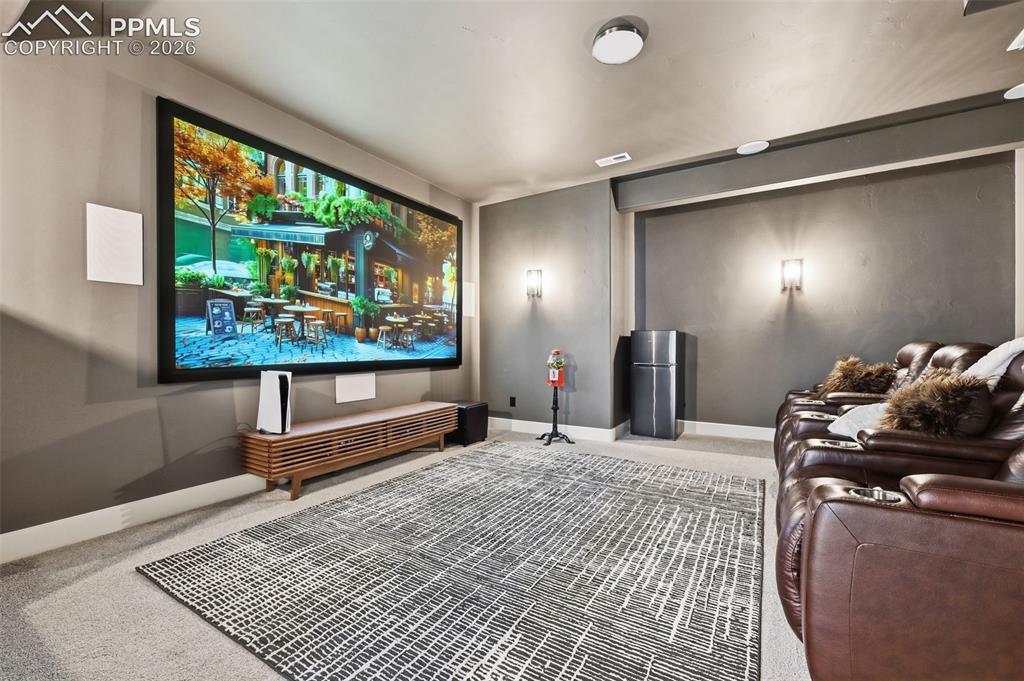 Image 31 of 39: Dedicated media room featuring a large projection screen, built-in wall spe