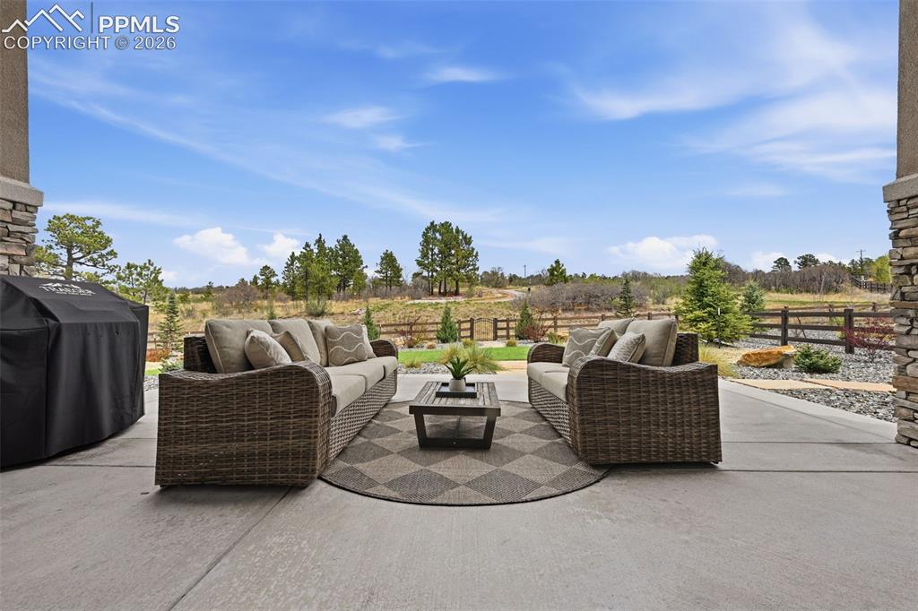 Image 36 of 39: Spacious outdoor patio featuring a concrete surface, stone veneer columns, 
