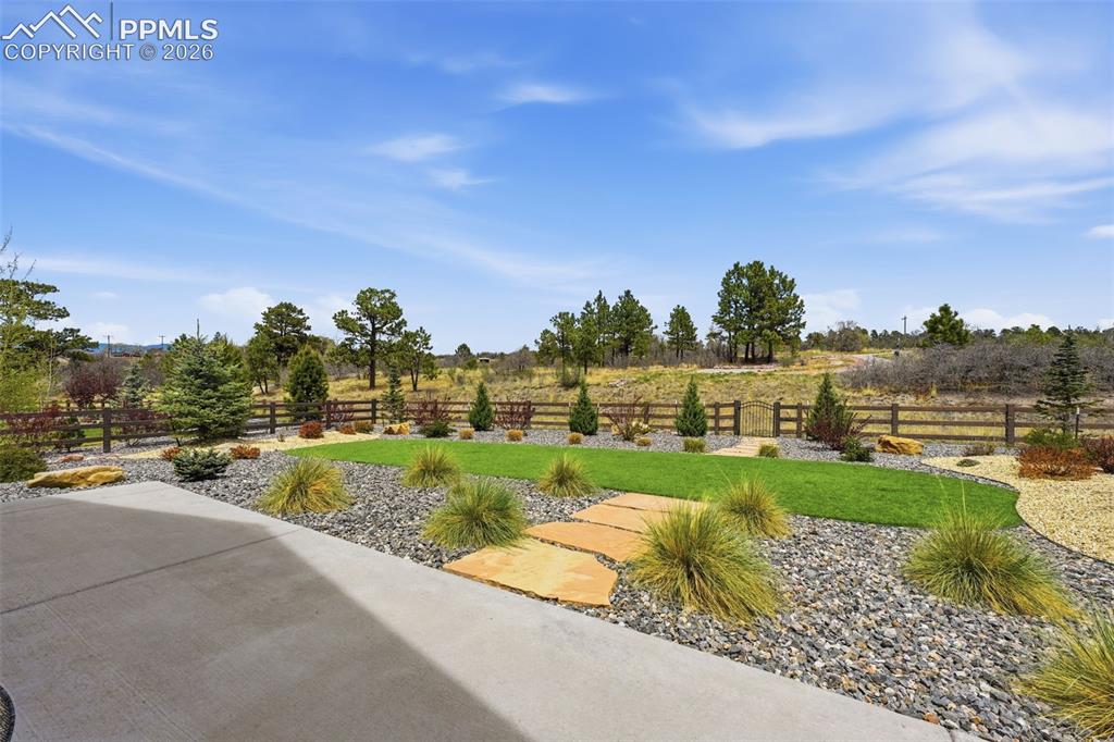 Image 37 of 39: Expansive backyard featuring a concrete patio, decorative stone landscaping