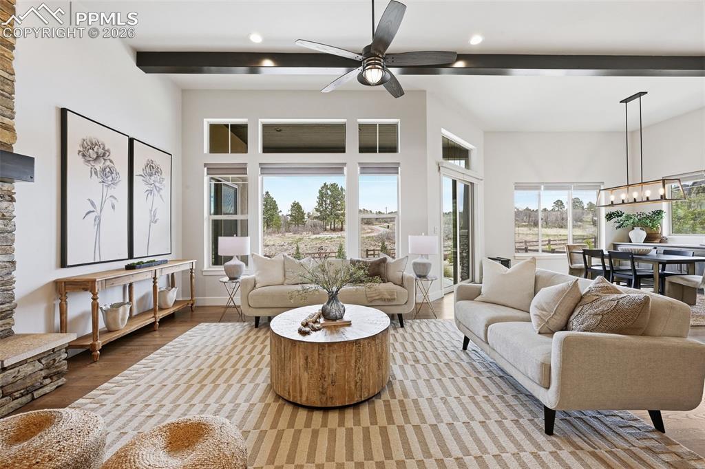 Image 5 of 39: Spacious living area featuring large windows, wood-finish flooring, a stone