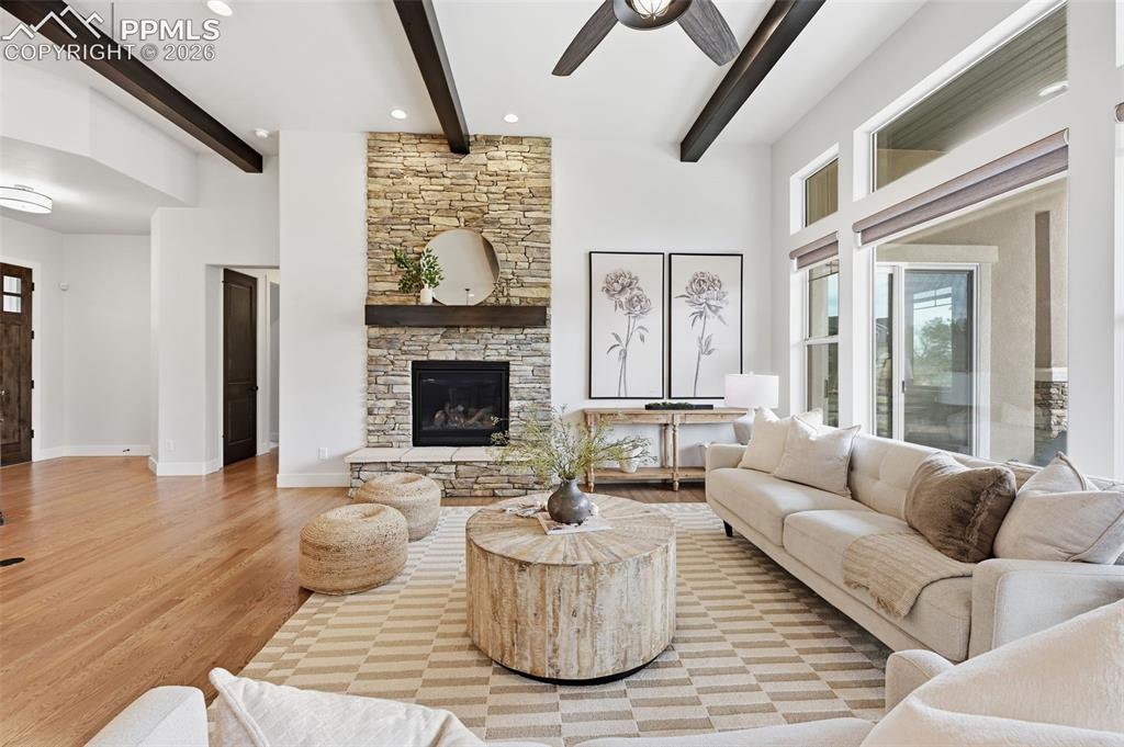 Image 6 of 39: Spacious living area featuring a stone-clad fireplace with a dark wood mant