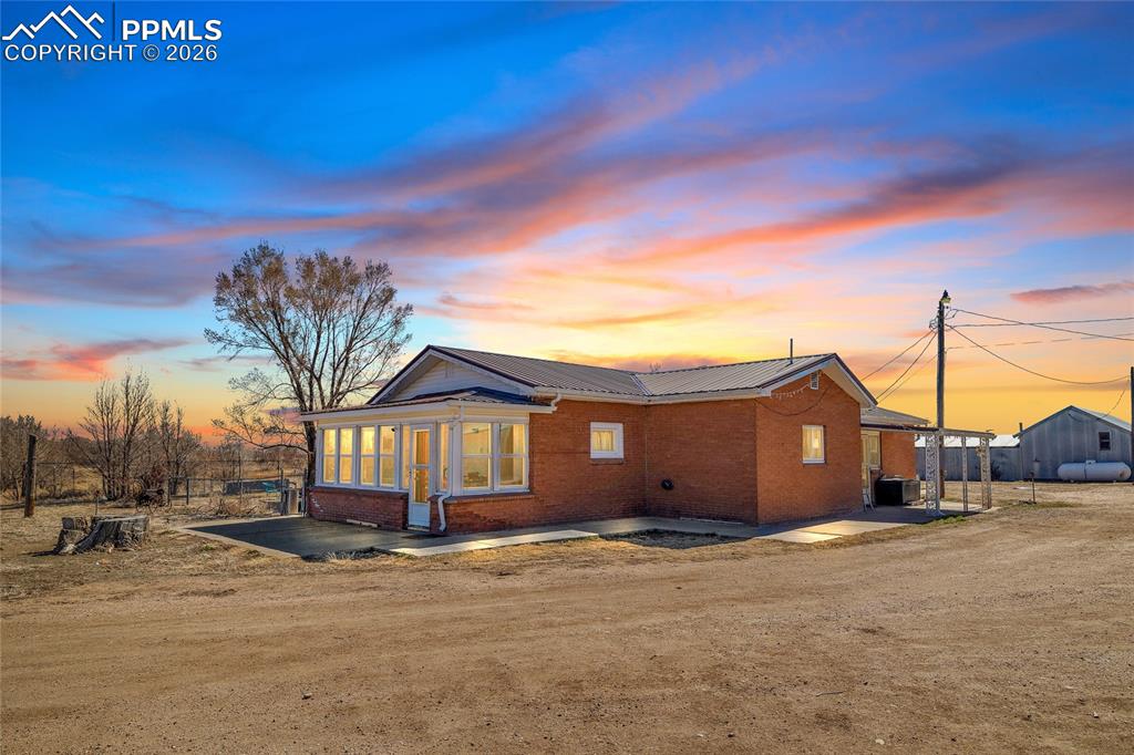 Caption: Back of property featuring brick siding, a metal roof, and a patio