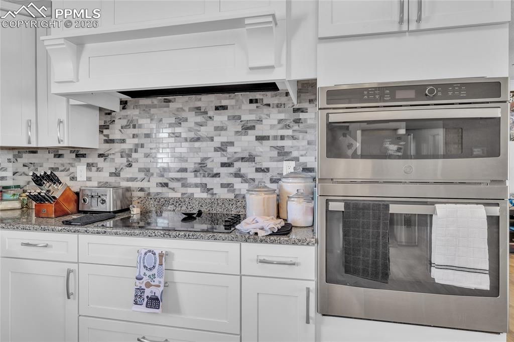 Image 29 of 49: Kitchen with white cabinets, open shelves, stainless steel appliances, ligh